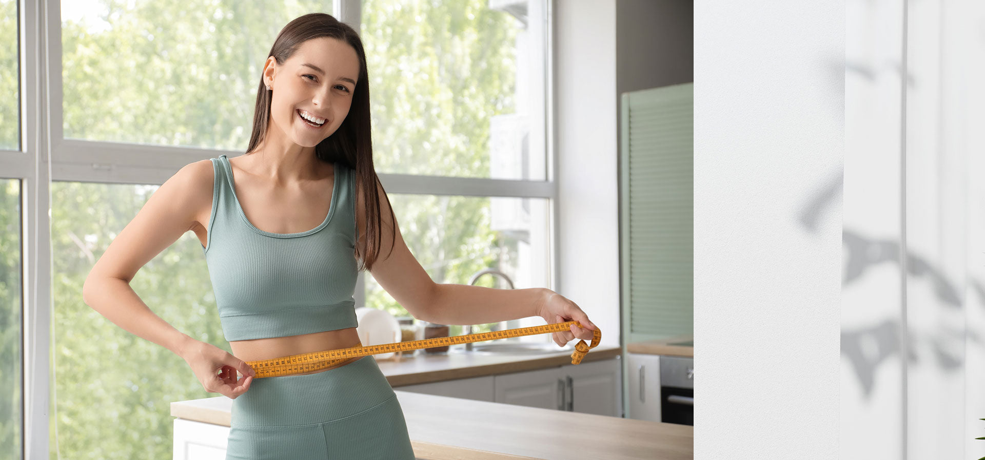 Woman measuring herself with a tape measure in a bright room