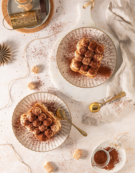 Two plates of dessert with a small bowl of cinnamon on a light surface.