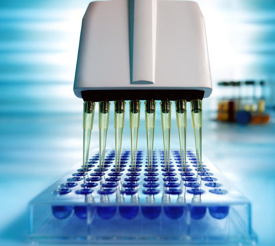 Lab equipment with test tubes containing a green liquid on a blurred laboratory background
