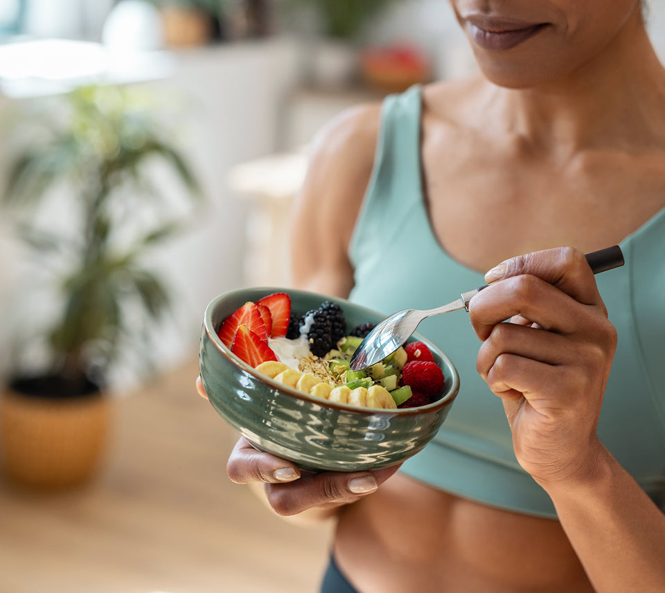 Woman holding a bowl of fruit salad with a blurred indoor background