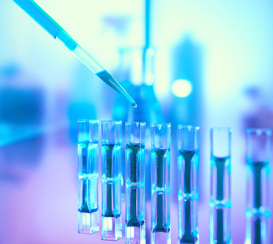 Laboratory setting with test tubes and a pipette, illuminated with blue light.